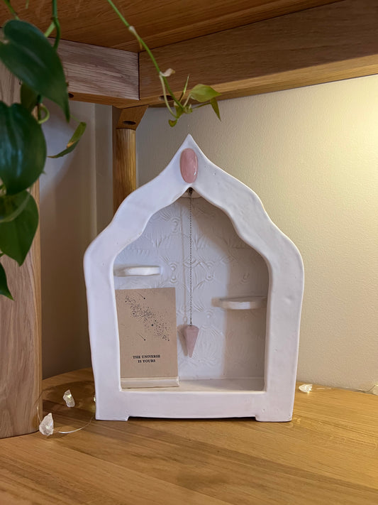 WHITE HOME-SHAPED CERAMIC ALTAR WITH TWO CANDLE HOLDERS, ROSE QUARTZ & ROSE QUARTZ PENDULUM – STAMPED